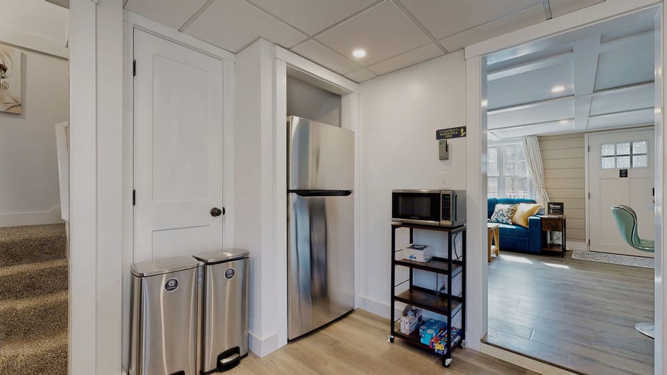 Refrigerator, microwave, trash, and recycling. The stairway to upstairs.