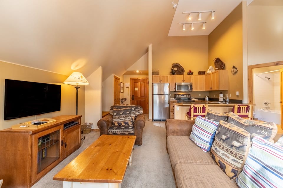 Relax in your cozy mountain retreat with warm wood accents, plush seating, and an open-plan design connecting your living space to the fully-equipped kitchen.