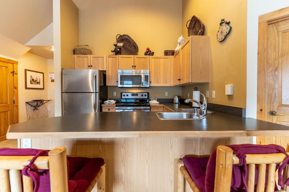 Your fully equipped kitchen features modern appliances and a breakfast bar where you can start each morning with coffee and mountain views.