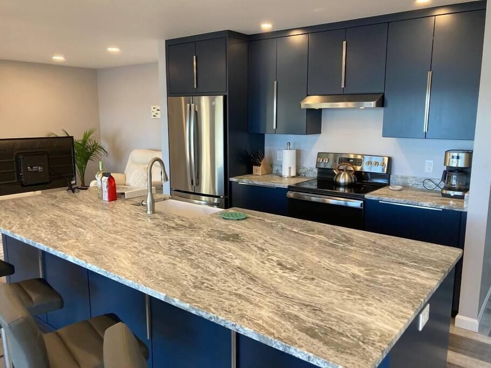 Stone countertop with eat-in bar and gourmet kitchen with modern custom-made cabinets