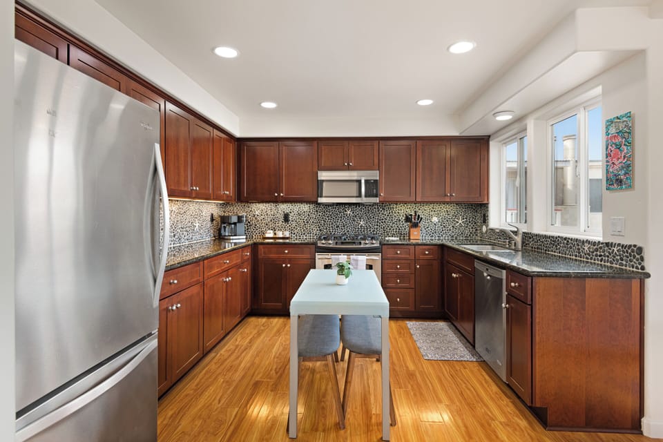 Modern kitchen equipped with stainless steel appliances, quartz countertops, and kitchen island or dining table