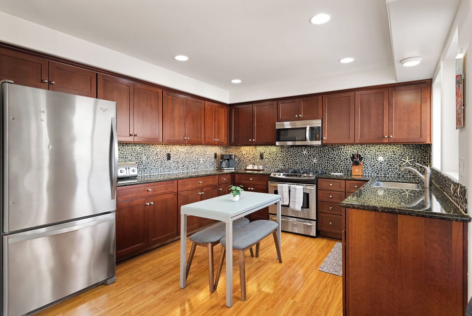 Modern kitchen equipped with stainless steel appliances, quartz countertops, and kitchen island or dining table