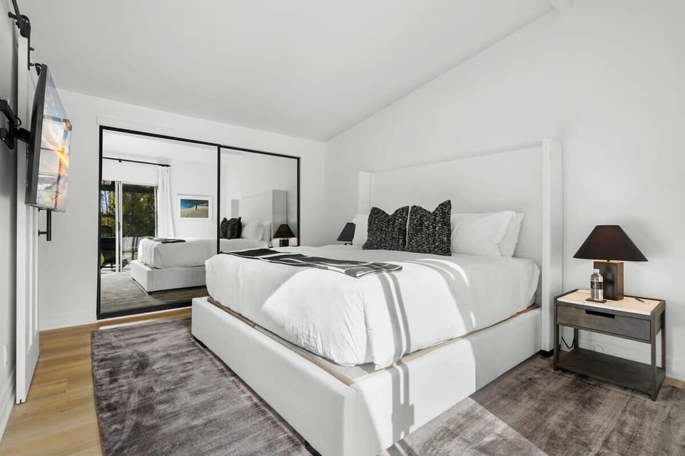 Luxurious master bedroom featuring large performance rug, marble side lamps, linen bed with hotel style linens and jute woven accent pillows, cashmere throw blanket, 55 inch flat screen smart TV. Ensuite bath with shower. Blackout shades.