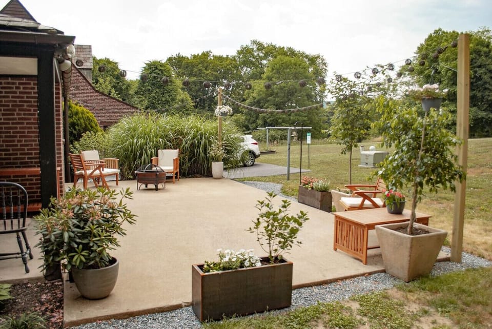 Outdoor patio with seating, plants, and string lights in a garden setting