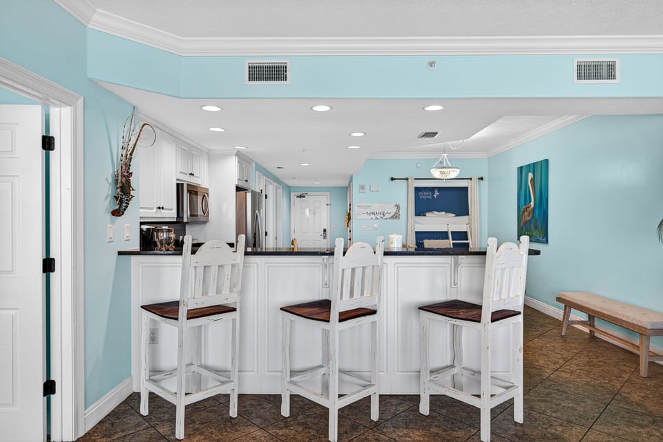 Coastal kitchen with a breakfast bar and white wooden stools.