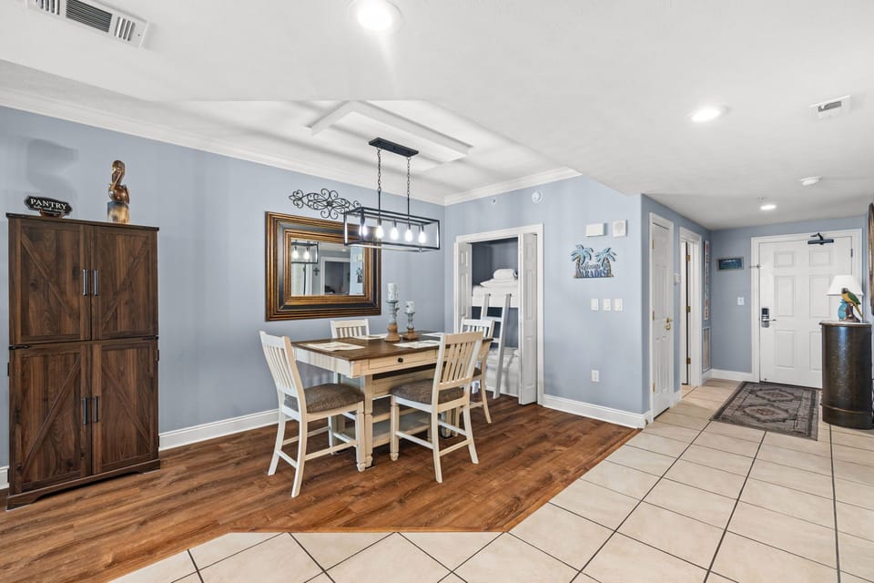 Step into a welcoming dining space where soft blue walls and warm wood floors create a peaceful atmosphere. Gather around the inviting table under modern lighting, perfect for shared meals and memories.