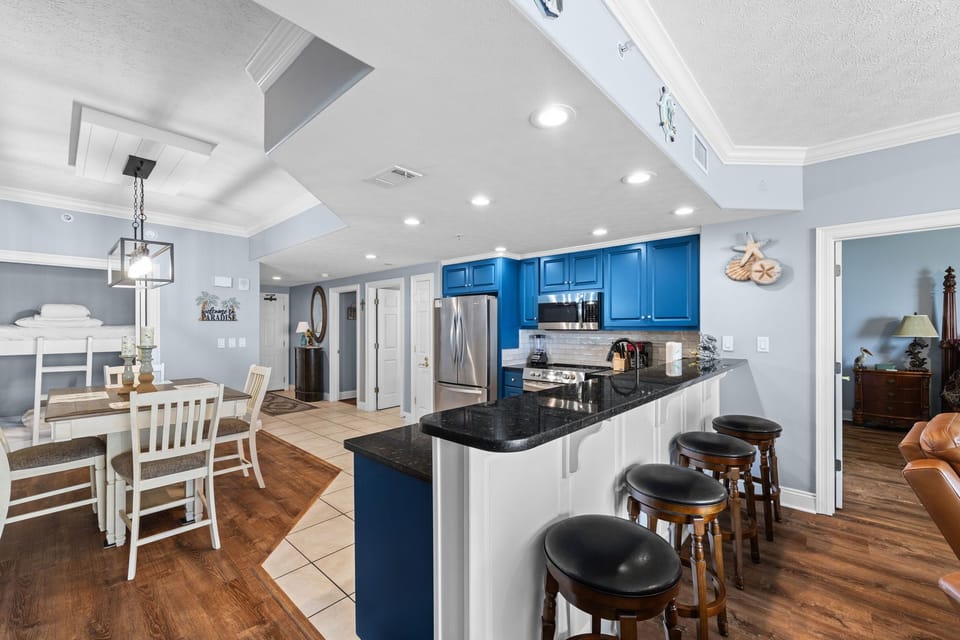 Step into your coastal retreat featuring a bright, open-concept kitchen and dining area with nautical touches, polished granite counters, and sleek stainless appliances—perfect for cooking and gathering together.