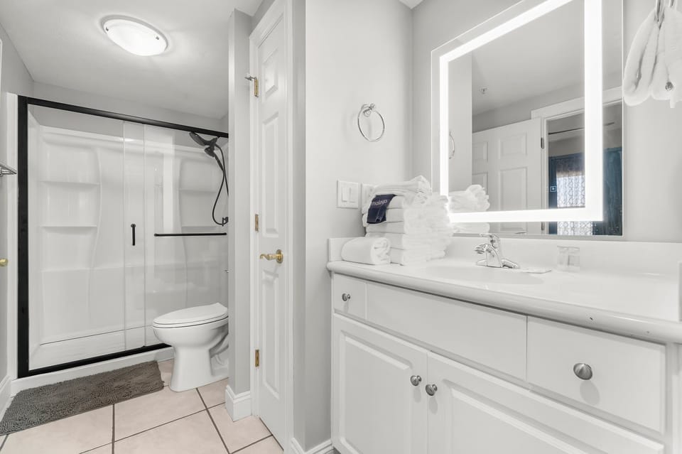 Modern bathroom with illuminated mirror and glass shower enclosure
