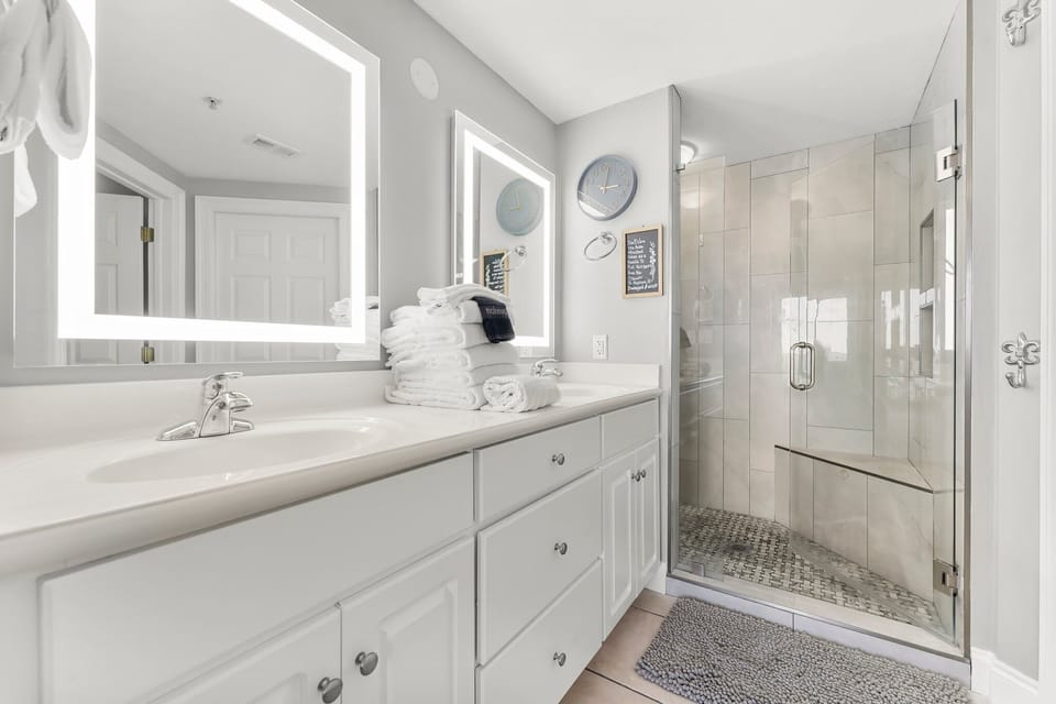 modern bathroom with illuminated mirrors and a glass-enclosed shower