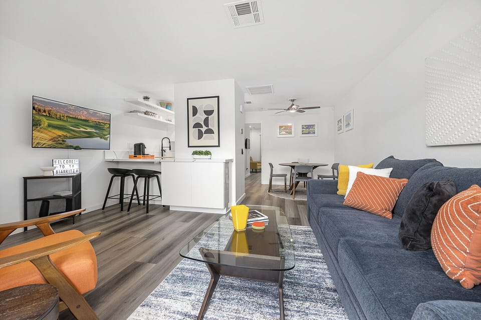 - Bright open concept Palm Springs condo connecting living room kitchen and dining area   - Modern decor and wood floors create a stylish desert inspired space   - Comfortable layout designed for relaxing and entertaining with ease
