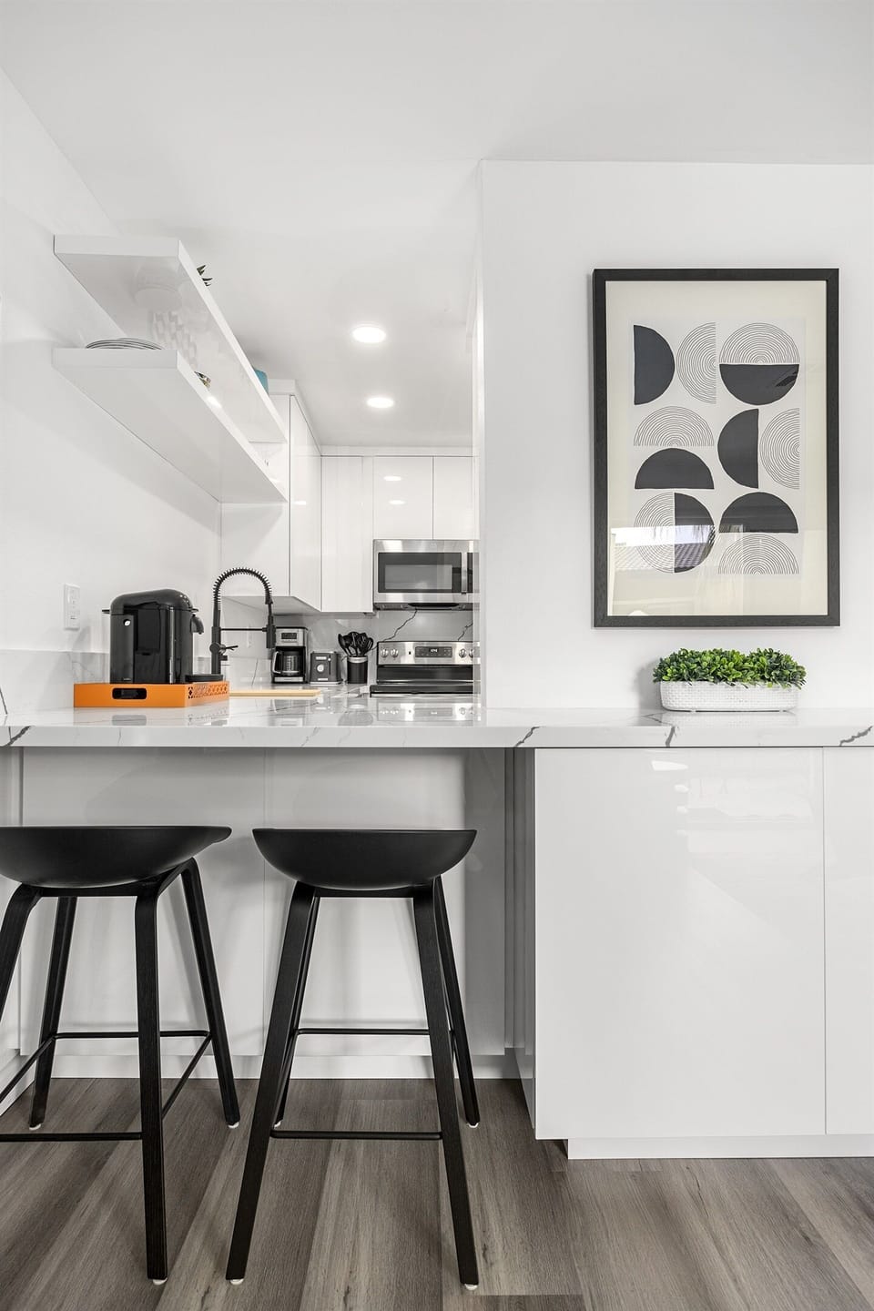 - Sleek breakfast bar with modern black stools and glossy white cabinetry   - Bright kitchen counter featuring espresso setup and stainless appliances   - Perfect spot for morning coffee or quick meals in a stylish setting