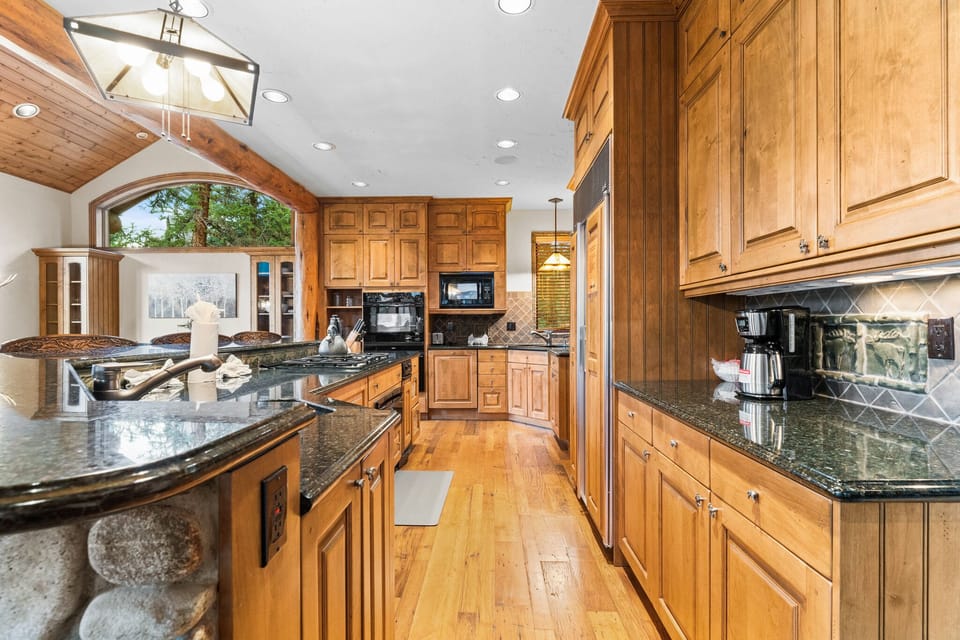 Cook memorable meals in this stunning gourmet kitchen featuring rich wood cabinetry, granite countertops, and high-end appliances perfect for your culinary adventures.