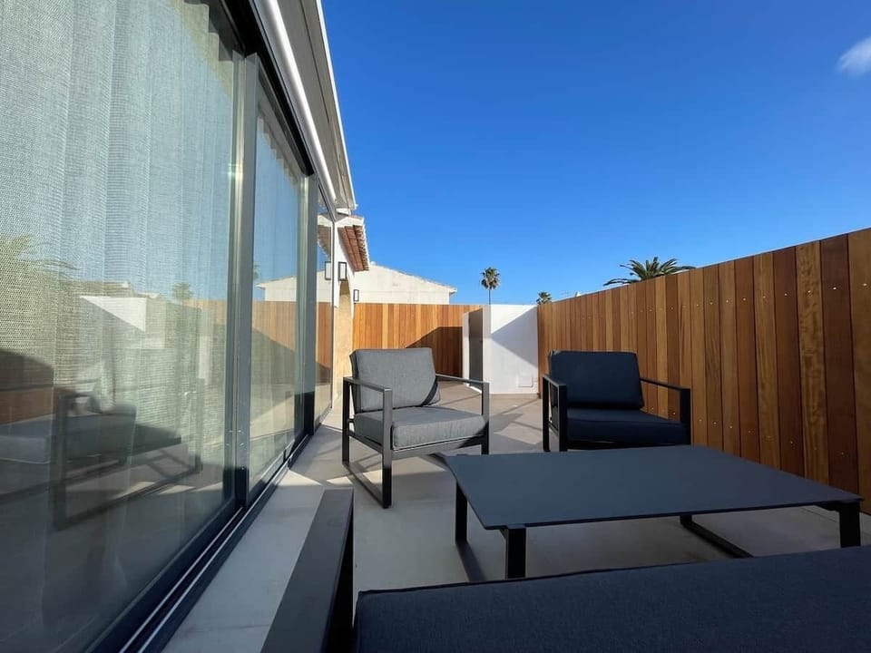 Gran terraza de 40m2 orientación sur con gran toldo automático con mando a distancia y conjunto de sofás y mesa para 5 personas con preciosa valla de iroko natural.