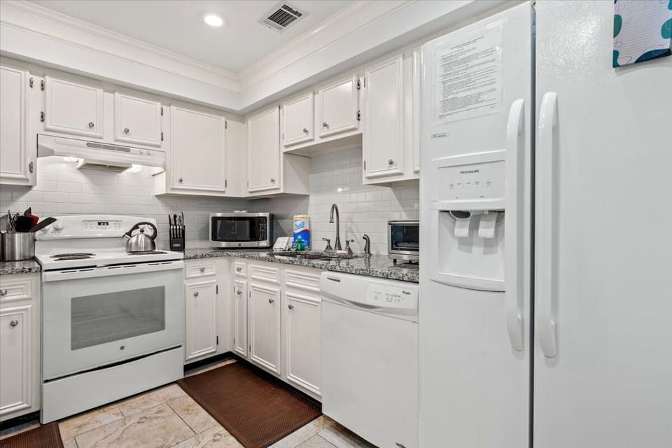 Your fully-equipped kitchen features crisp white cabinets, granite counters, and all modern appliances for preparing memorable meals during your stay.