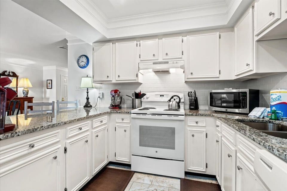Your fully equipped kitchen awaits with granite counters, white cabinets, and all appliances needed for memorable meals.
