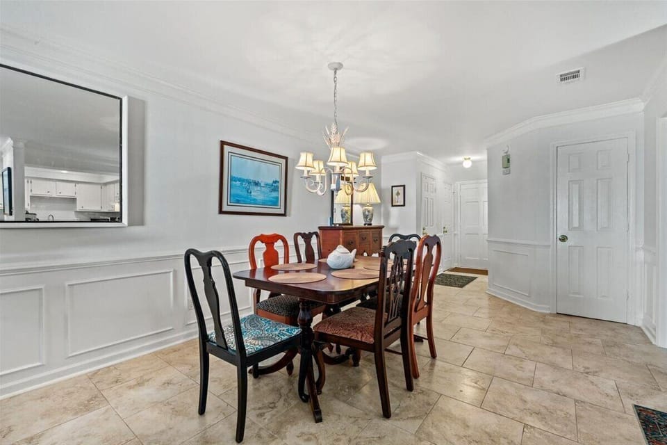 Gather around this elegant dining table where conversations flow as smoothly as the warm light from your chandelier overhead.