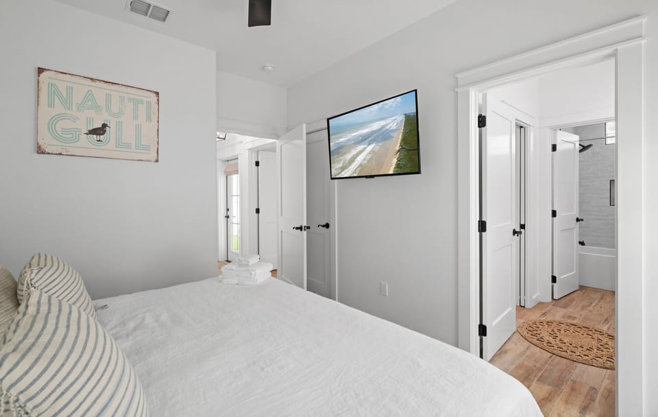 Bedroom 3 — King Bed, 'Nauti Gull' Sign, Wall TV, Closet & En-Suite Bath Doorway
