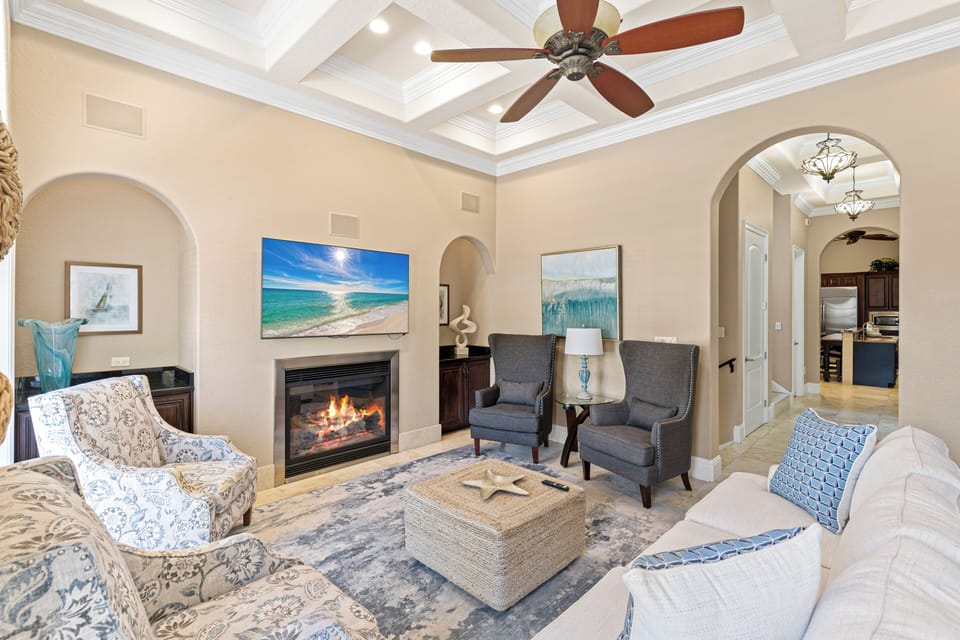 Curl up in this elegant living room where the fireplace's glow meets coastal charm, creating your perfect retreat.