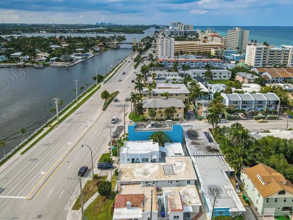 Aerial view of coastal city with beach, canal, and bridge—your Airbnb is close to it all.