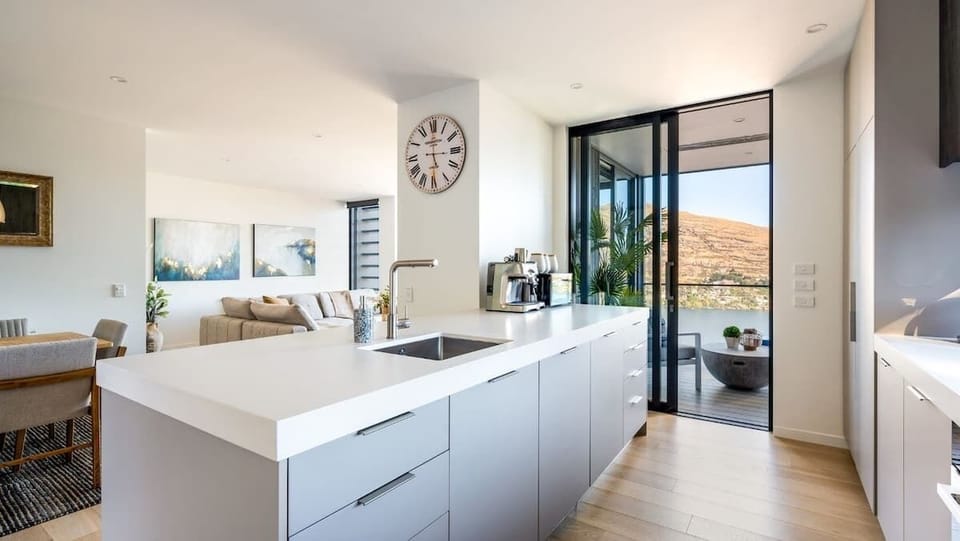 The sleek, modern kitchen is equipped with high-end appliances, ample counter space, and a coffee machine, making it ideal for preparing gourmet meals or enjoying a coffee break."