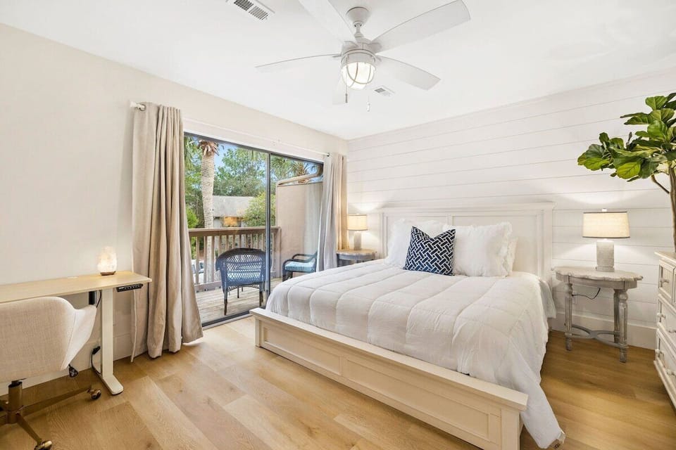 A spacious and grand master bedroom equipped with a flat screen TV, private balcony, and standing/sitting desk and workspace. 