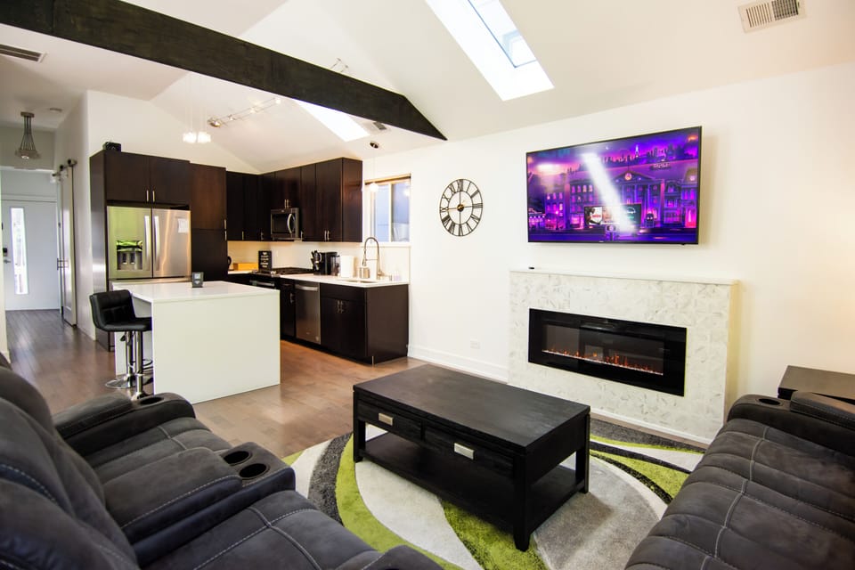 Bright open living space with skylights, fireplace, and modern kitchen