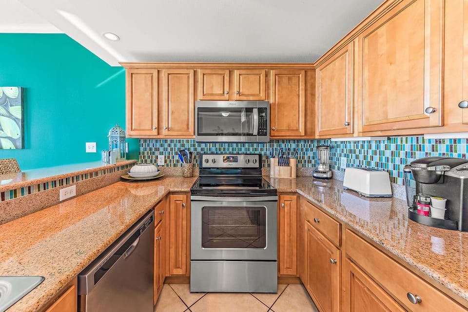 Discover culinary convenience in this well-appointed kitchen, featuring granite countertops, modern stainless steel appliances, and a vibrant tile backsplash. Perfectly equipped for preparing delicious meals during your stay.