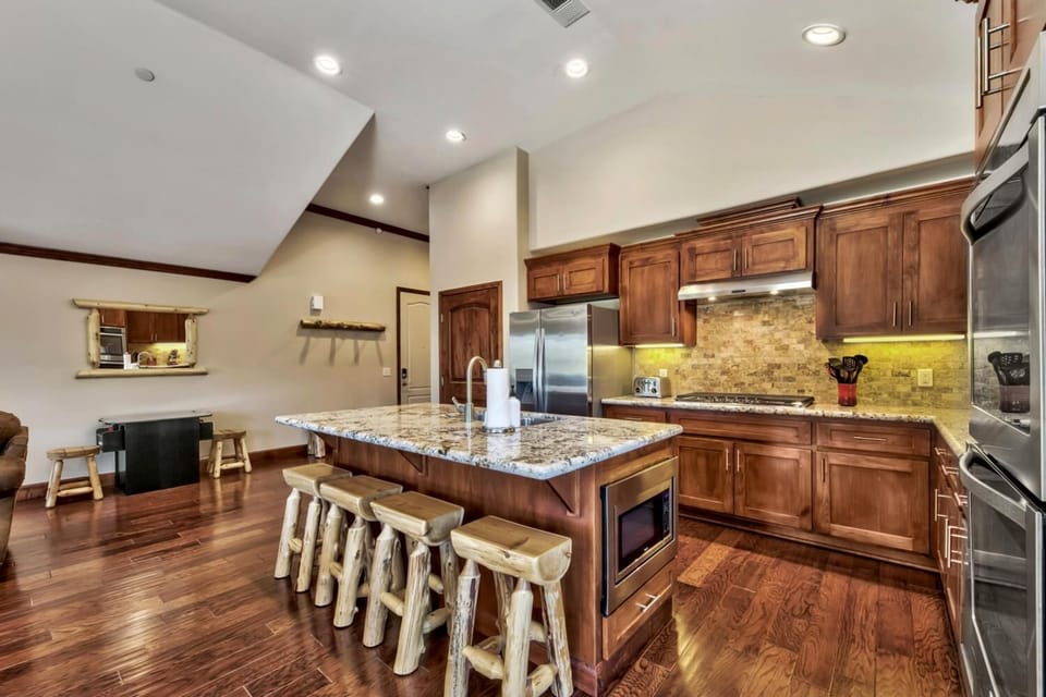 Gather around your gourmet kitchen island with granite countertops, rustic log stools, and rich hardwood floors for memorable meals together.