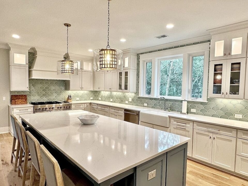 Large kitchen island with room for food preparation and seating, pendant lights.