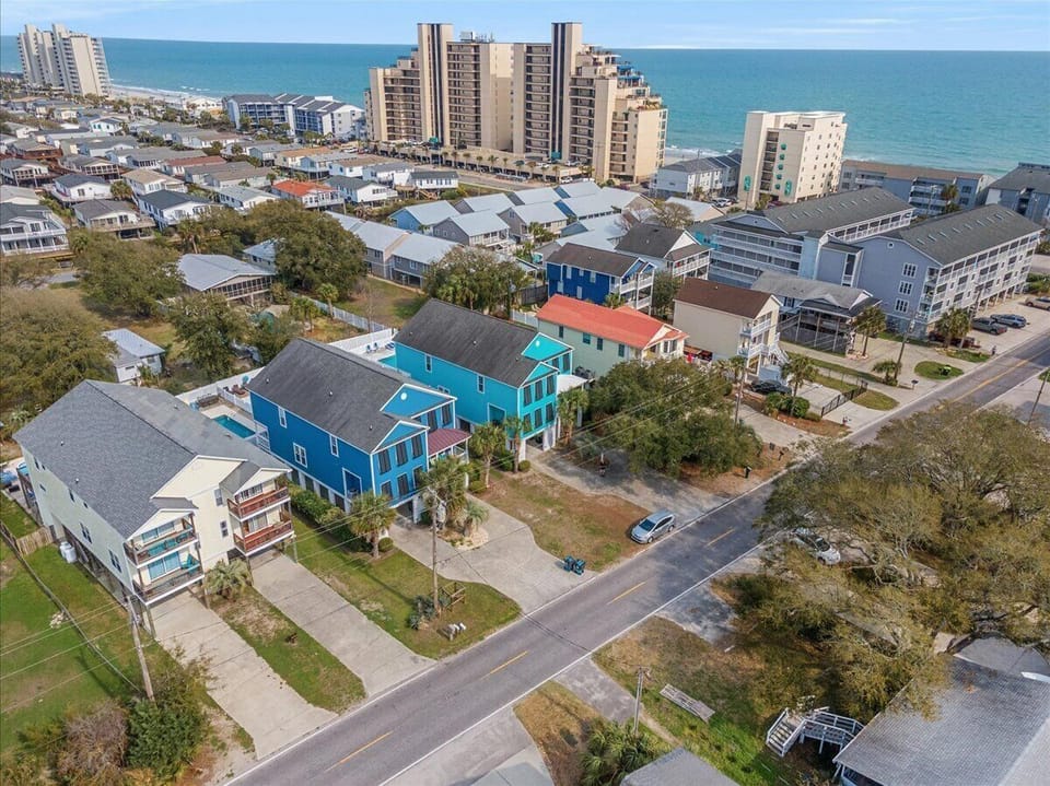 Aerial view of area featuring colorful coastal homes and high-rise buildings near the ocean.