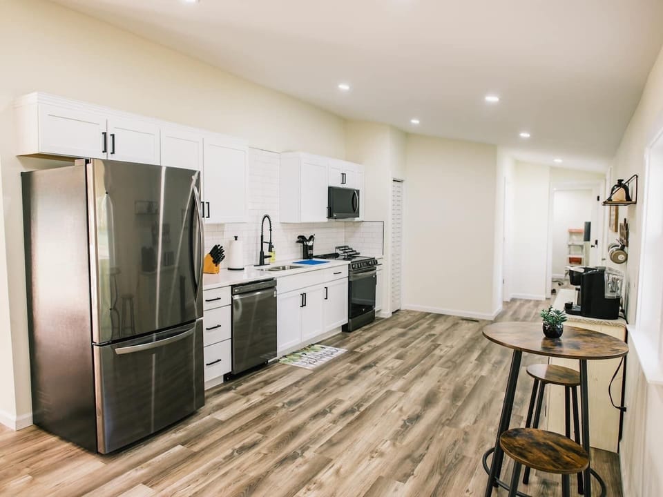 Spacious open kitchen with tiled backsplash and stainless steel appliances. Who gets to cook tonight?