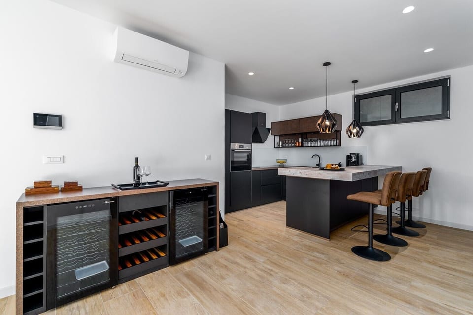Fully equipped Kitchen with a kitchen island, a wine cooler, dining area with a table .