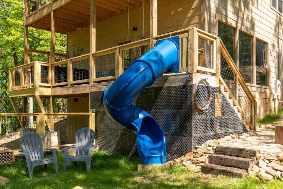 Outdoor deck with a blue spiral slide and seating area for family-friendly fun.