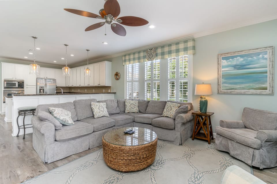 Relax in your bright, airy living space featuring plush sectional seating, a fully equipped kitchen, and coastal touches that create the perfect vacation atmosphere.
