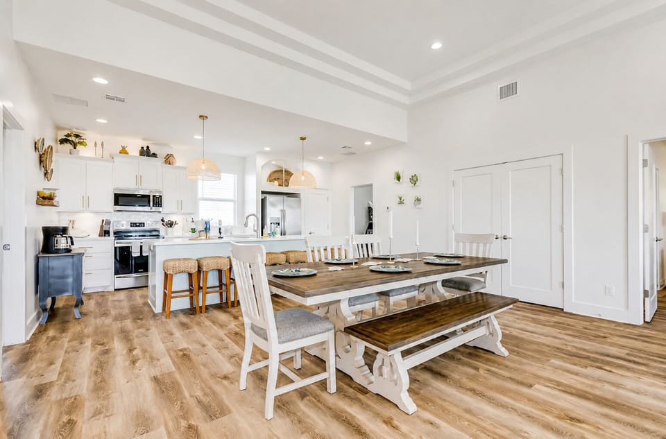 Bright open-concept living and dining area with modern coastal design, large table seating, and fully equipped kitchen in Bolivar Peninsula vacation home.