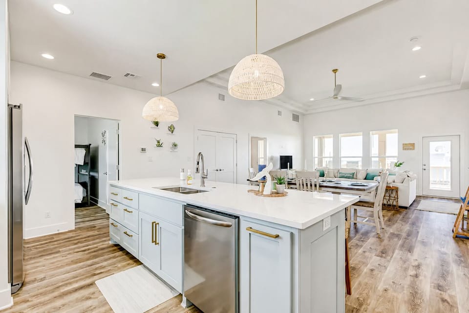 Open kitchen and living space with oversized island, pendant lighting, and dining area in a luxury Bolivar Peninsula vacation rental.