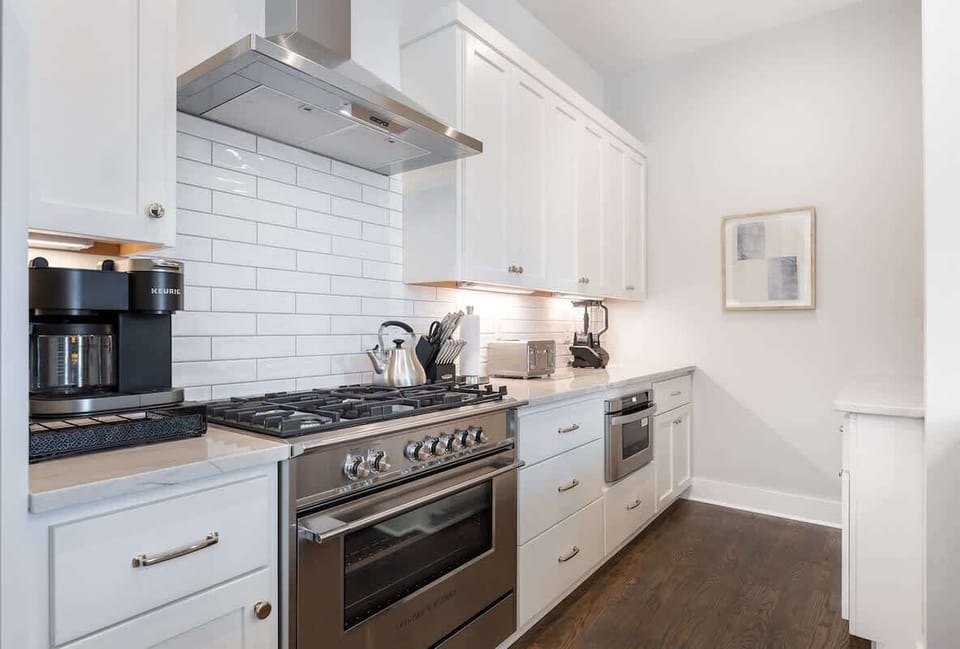 Contemporary white kitchen equipped with stainless steel appliances.
