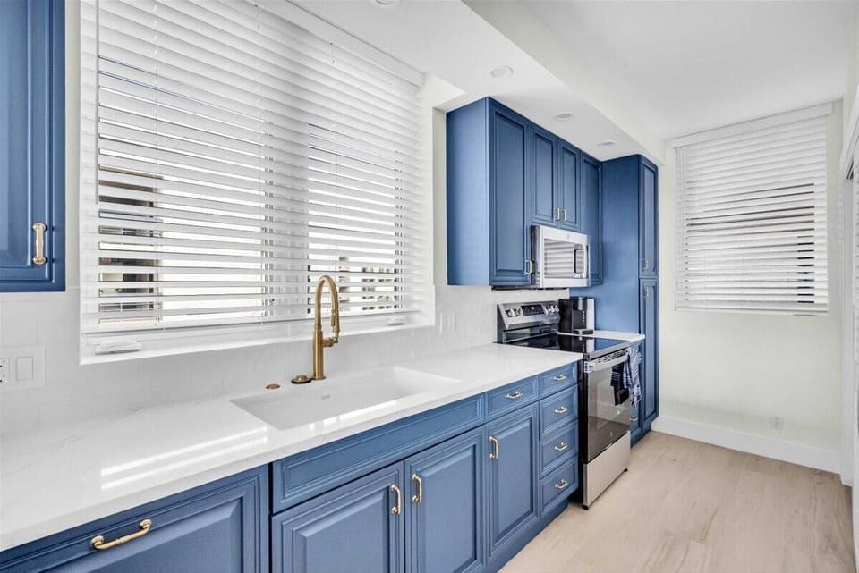 Bright kitchen with modern blue cabinetry and stainless appliances