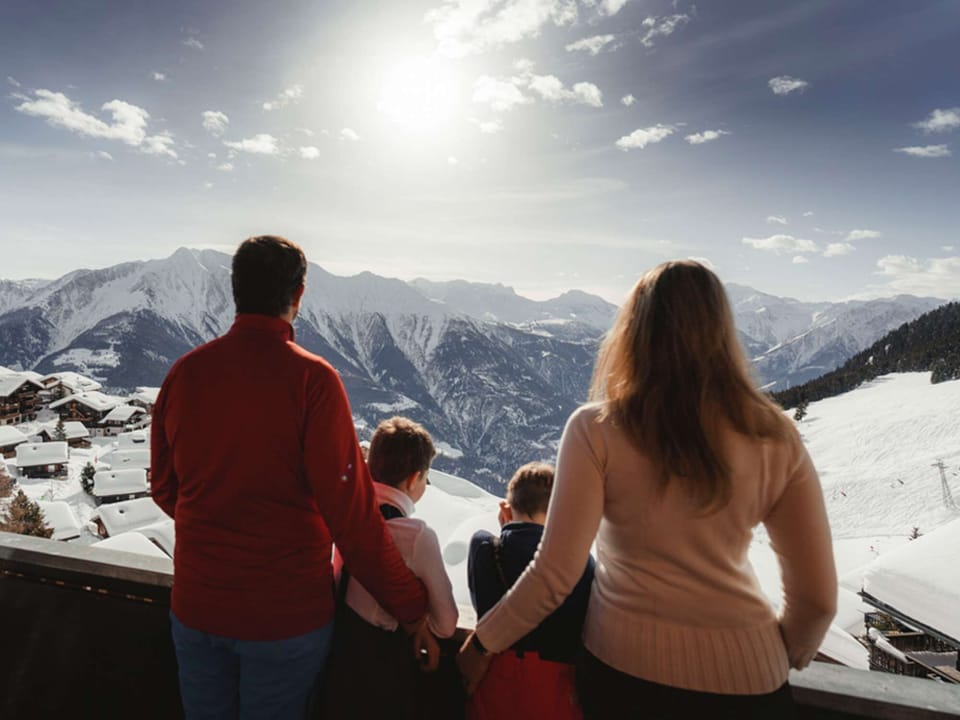 Family enjoys the Valais mountain panorama from the apartment balcony in winter