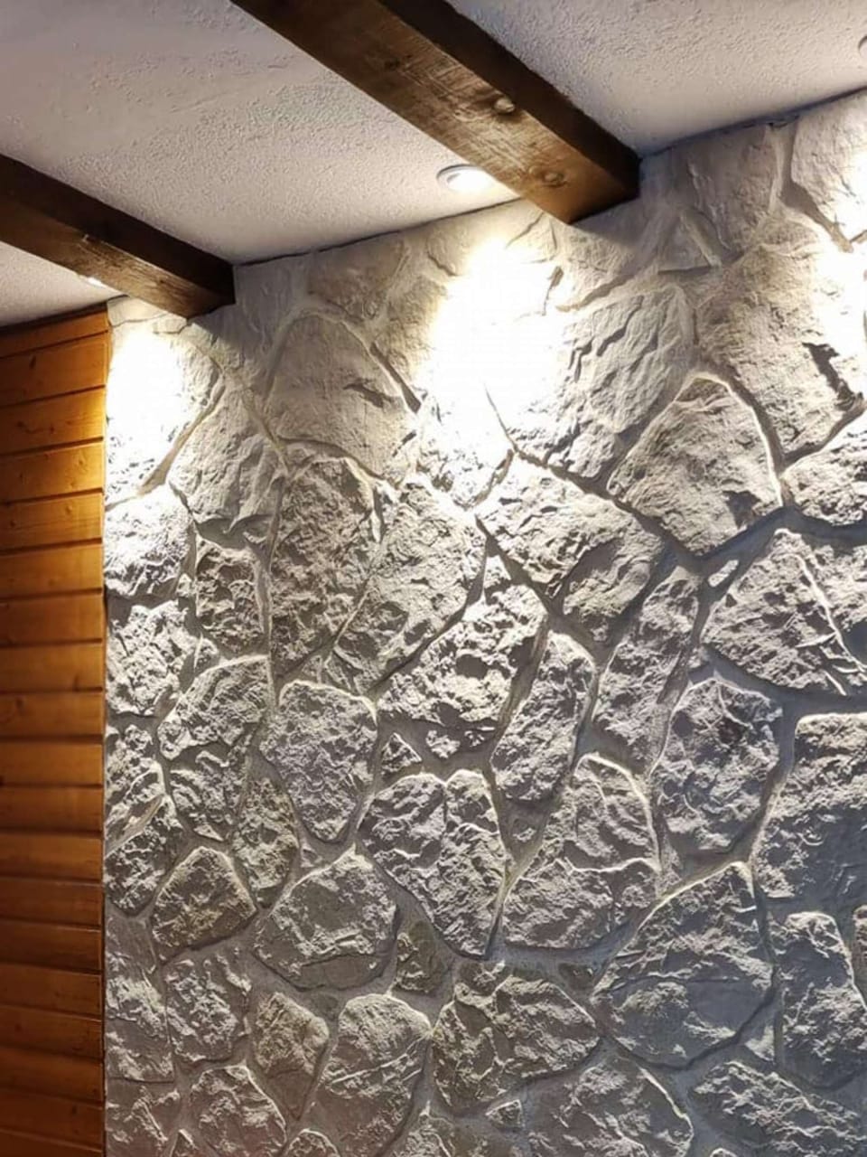 The indirect lighting of the quarry stone wall creates a charming atmosphere in the living room