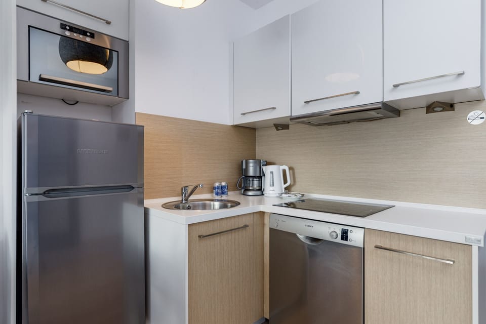 Kitchenette with induction hob, fridge with freezer, oven, microwave, electric kettle and coffee maker.