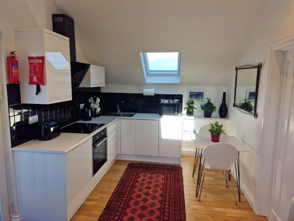 Vaulted modern kitchen with dishwasher & microwave. Dining table and chairs.