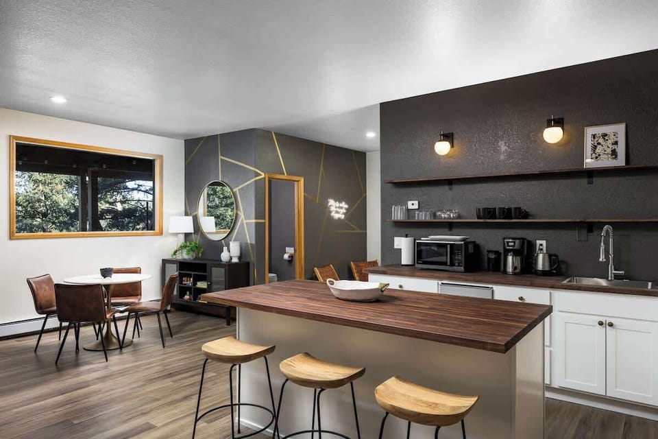 Downstairs kitchenette with butcher block, walnut stools, and entertainment zone.