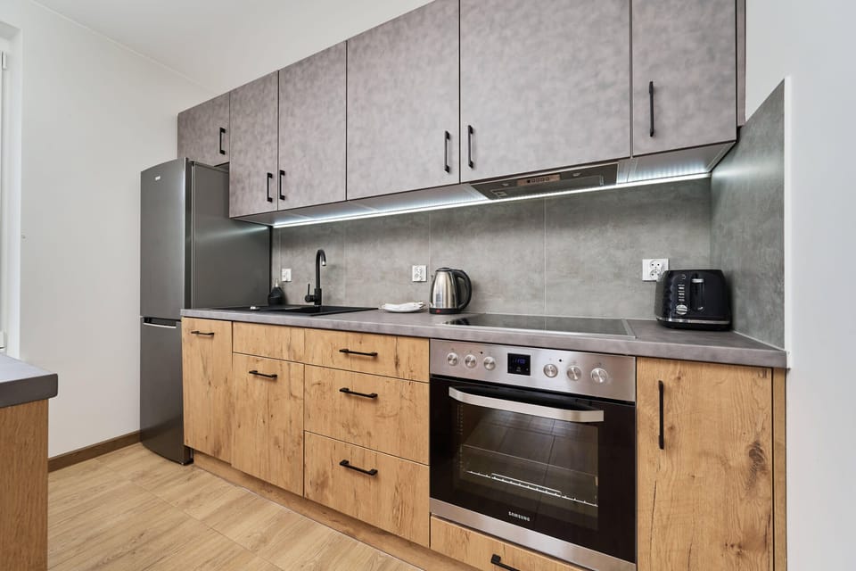 Kitchenette with electric hob, fridge, freezer, oven, kettle, toaster, dishwasher and kitchen utensils.