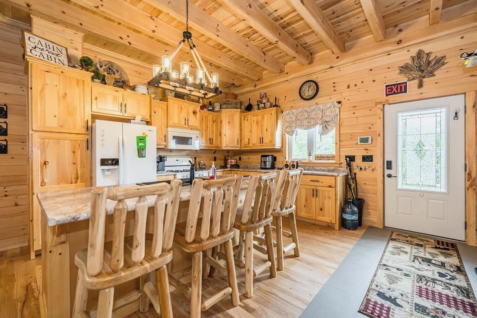 The awe-inspiring open concept kitchen, complete with a majestic island and handcrafted log bar-stools, is a hub of entertainment and warmth, inviting you to create culinary delights against the backdrop of the crackling fireplace.