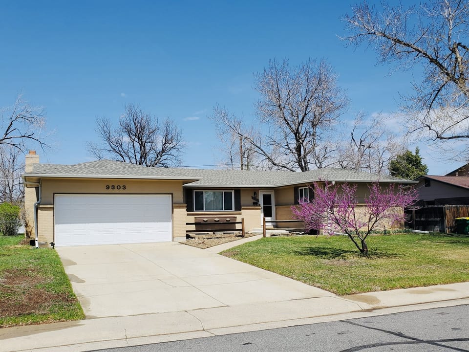 Beautifully landscaped front exterior with a large driveway and garage with private parking access. 