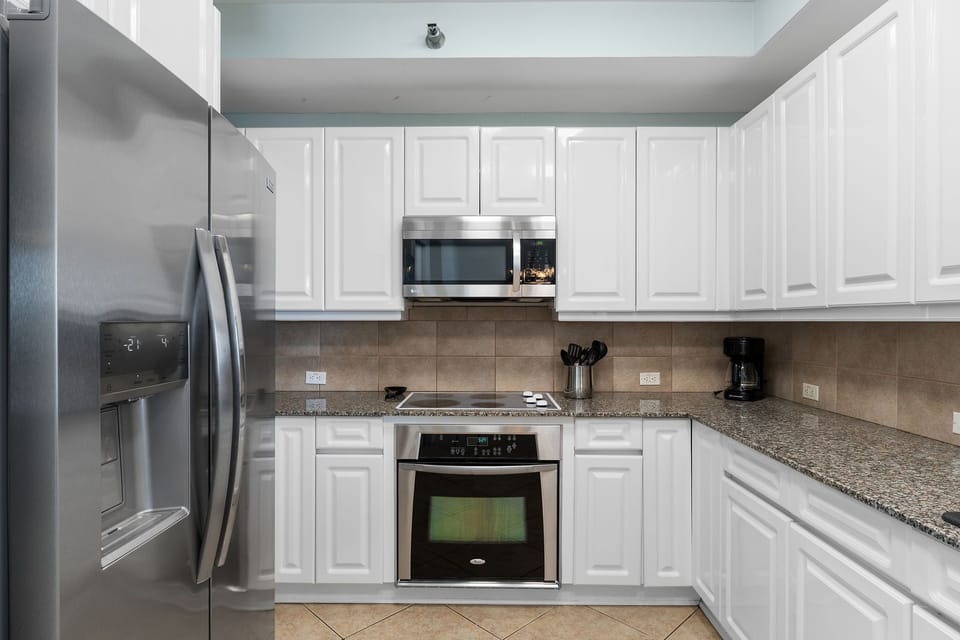 Beach Colony Tower 10C- Your fully equipped kitchen has everything you need: stainless steel appliances, granite countertops, crisp white cabinets, and space to prepare your favorite meals in comfort.