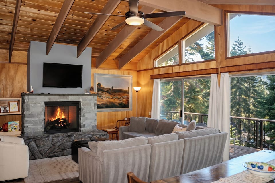 Vaulted wood ceilings, a cozy fireplace, and forest-view windows create the perfect mountain retreat setting.