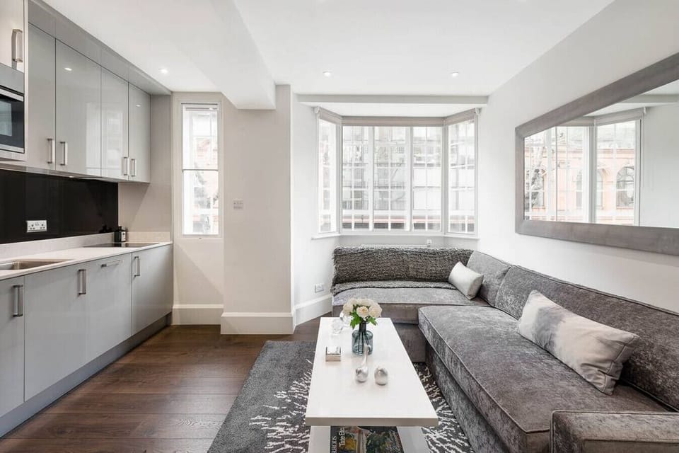 Living room — queen sofa bed always made up and ready to use with extra pillows and blankets provided, alongside a coffee table and open-plan living space with hardwood flooring and bespoke cabinetry