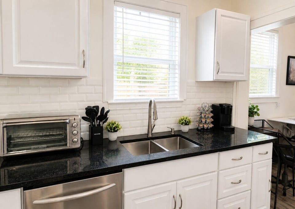 A bright, fully equipped kitchen with a Black+Decker air fryer/toaster oven, cooking utensils, and a Keurig with coffee pods: everything you need to cook, recharge, and start your morning with a fresh cup of coffee.